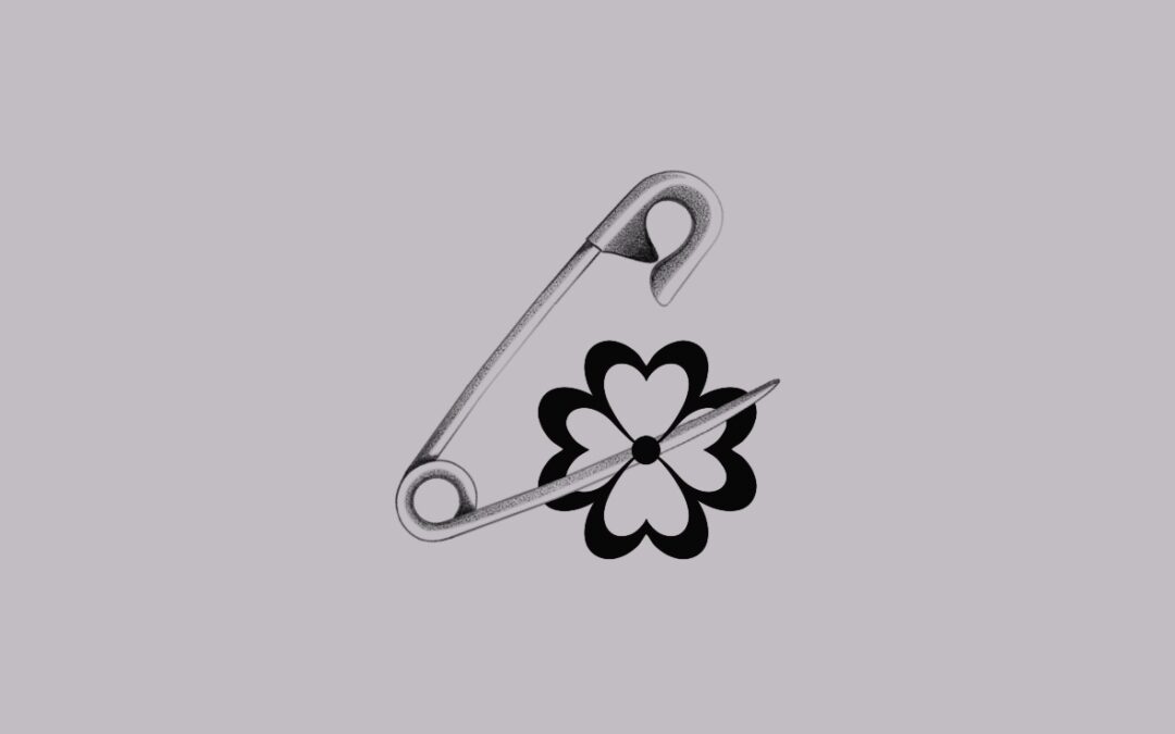 A small delicate tattoo desing of a safety pin and a flower